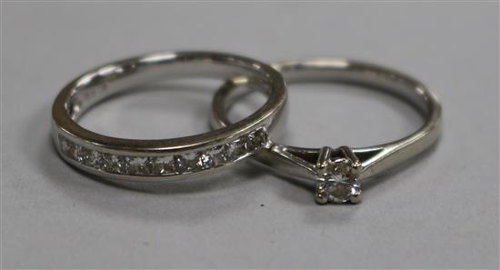 A modern 18ct white gold and diamond set half eternity ring and a 9ct white gold and solitaire diamond ring.